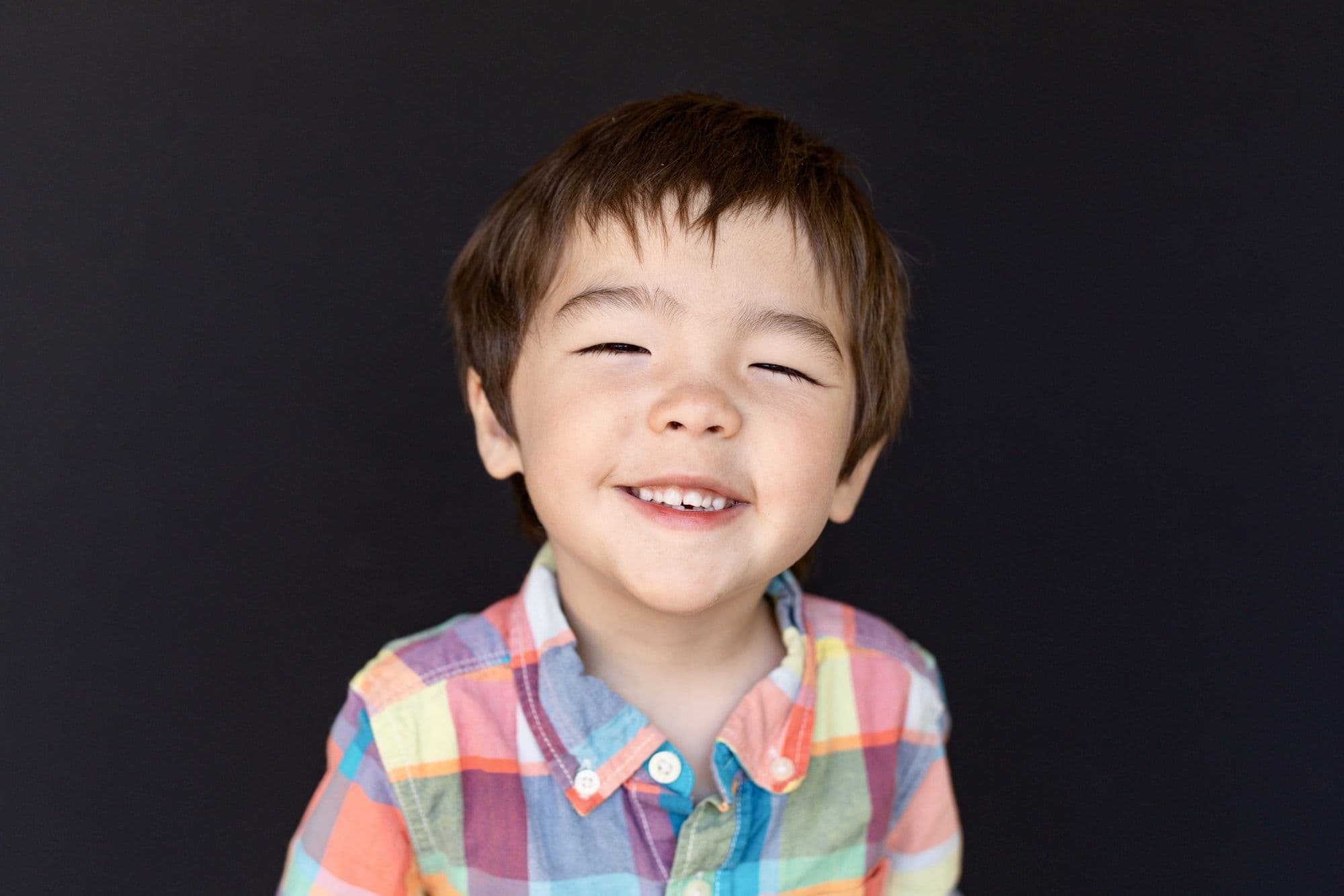 Professional school portrait by San Francisco photographer featuring young boy in vibrant plaid shirt