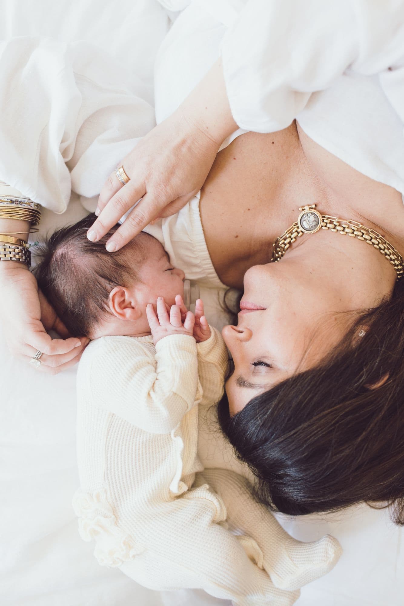 Mother bonding with newborn baby wearing cream sweater in San Francisco