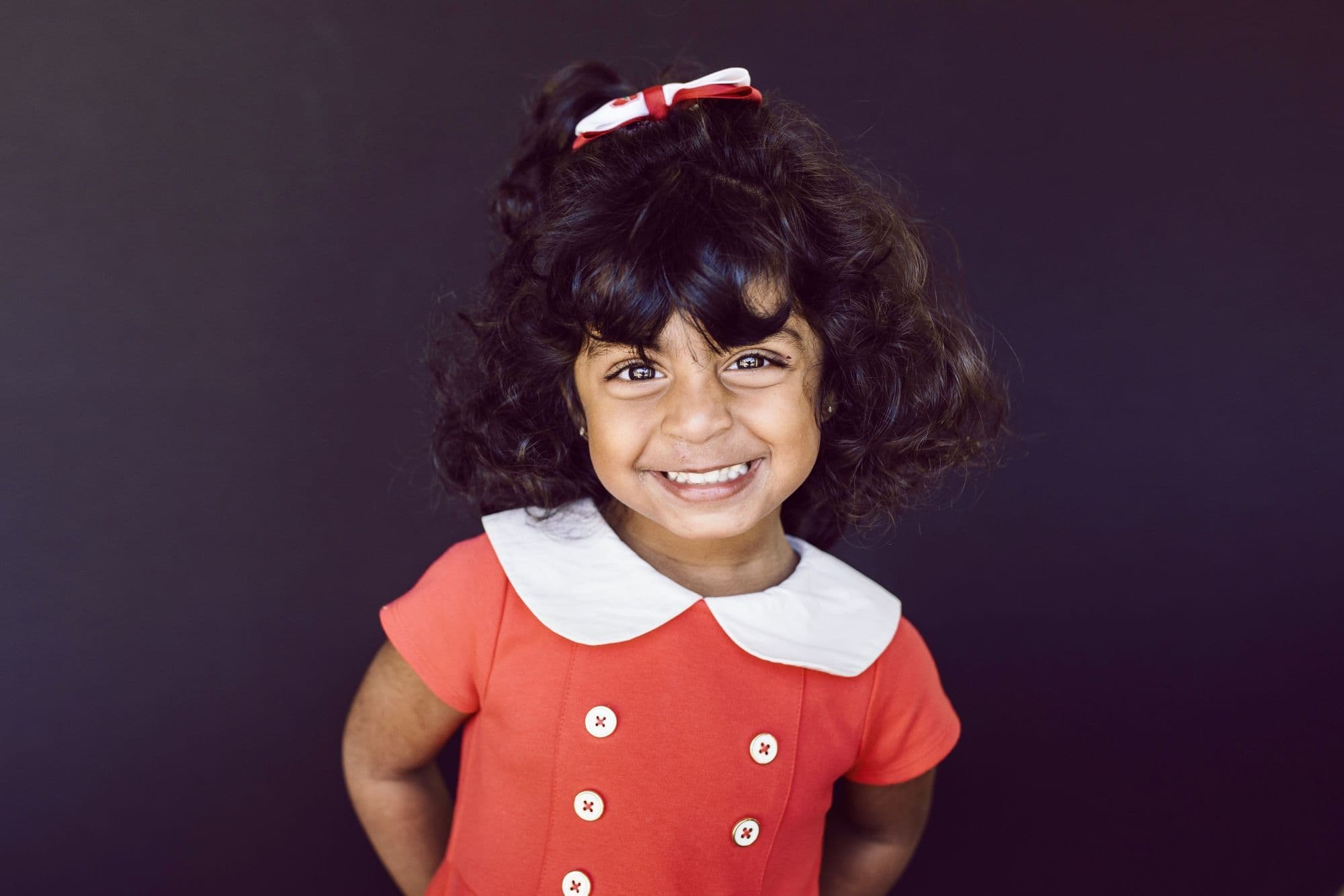 Professional school portrait by San Francisco photographer featuring student in red dress with white collar