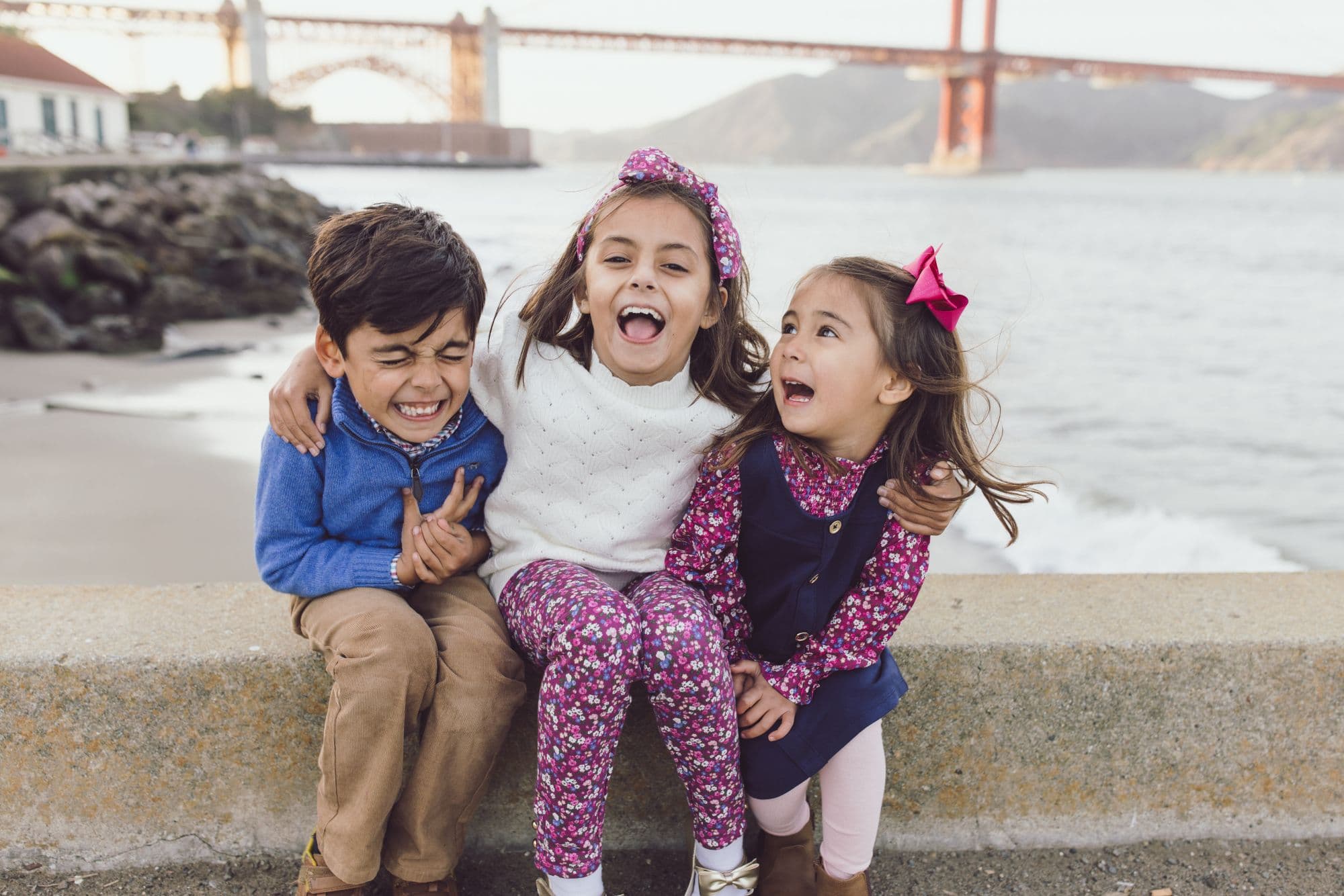 Three children smiling during a family photo session at Crissy Field in San Francisco