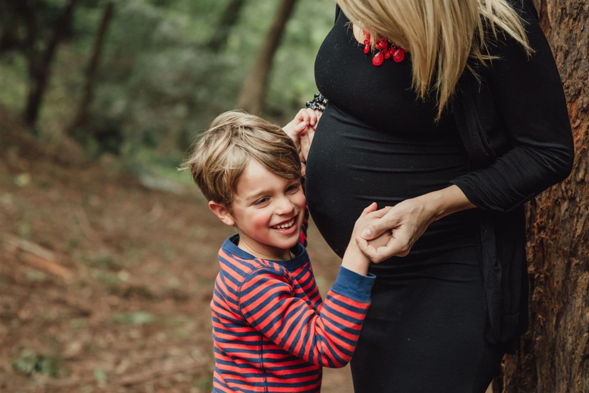 Mother and son bonding moment in forest during maternity photography session